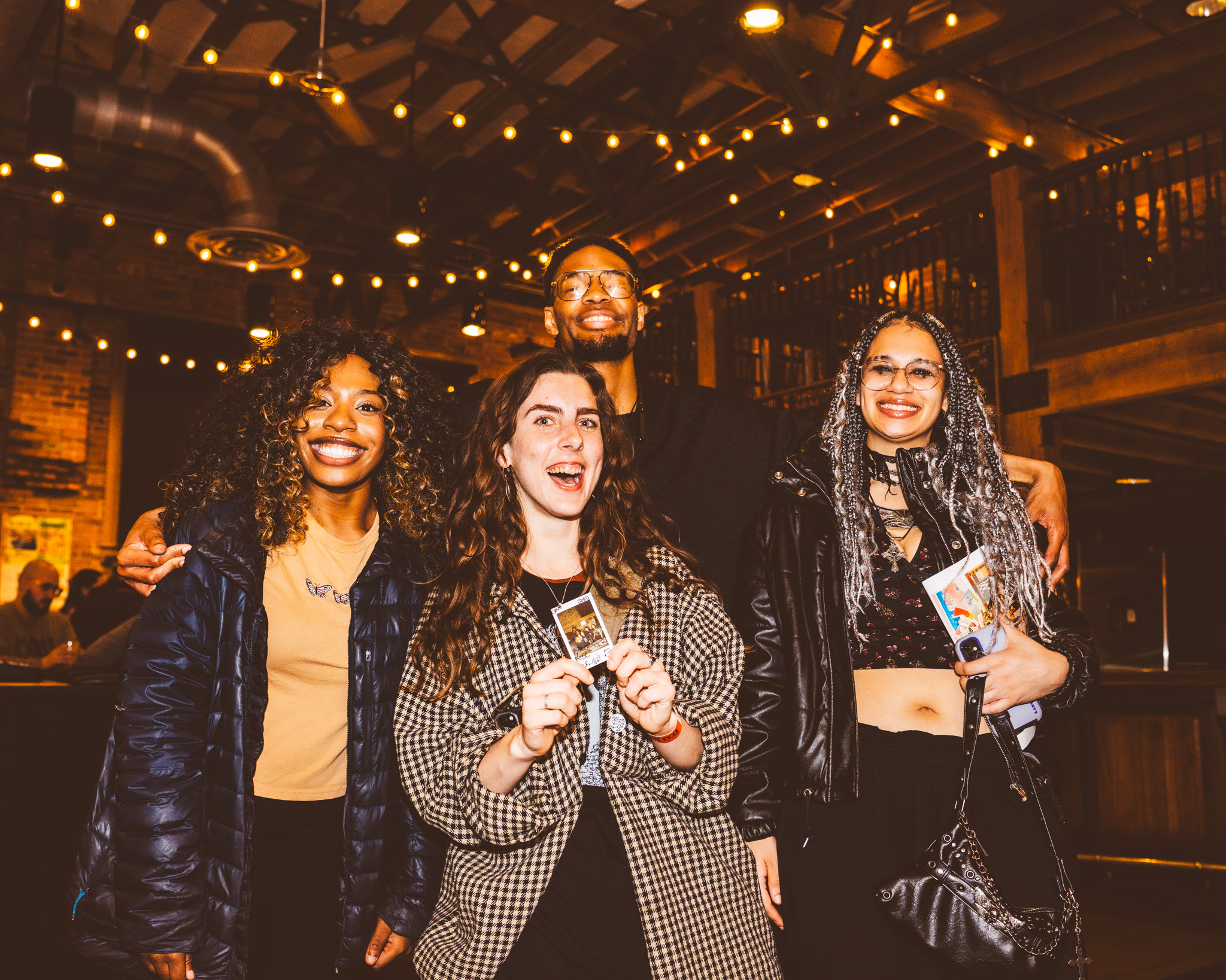 Four community members smiling together indoors at an event.
