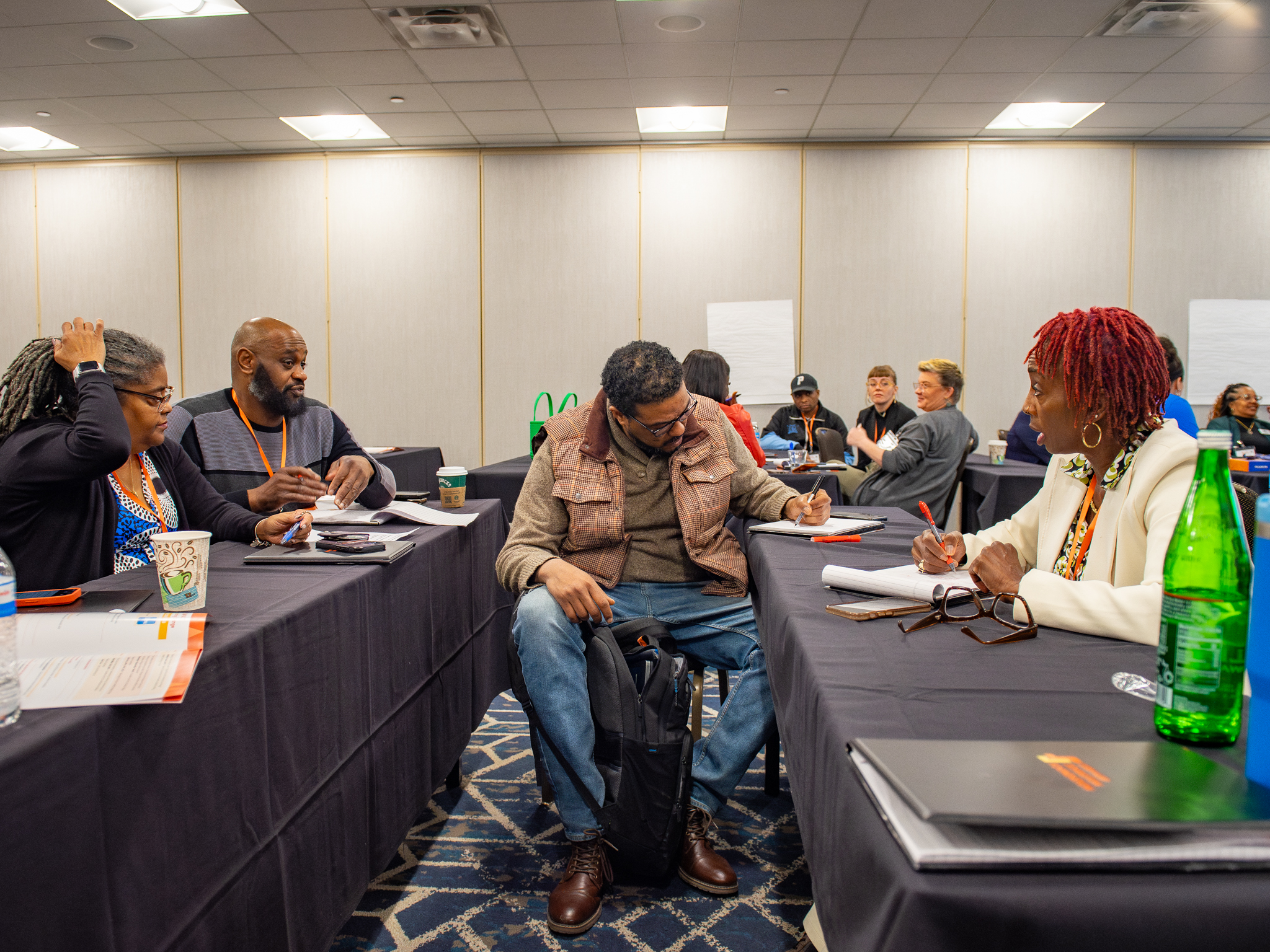 Community partners in a conference room, with a man at the center writing on paper